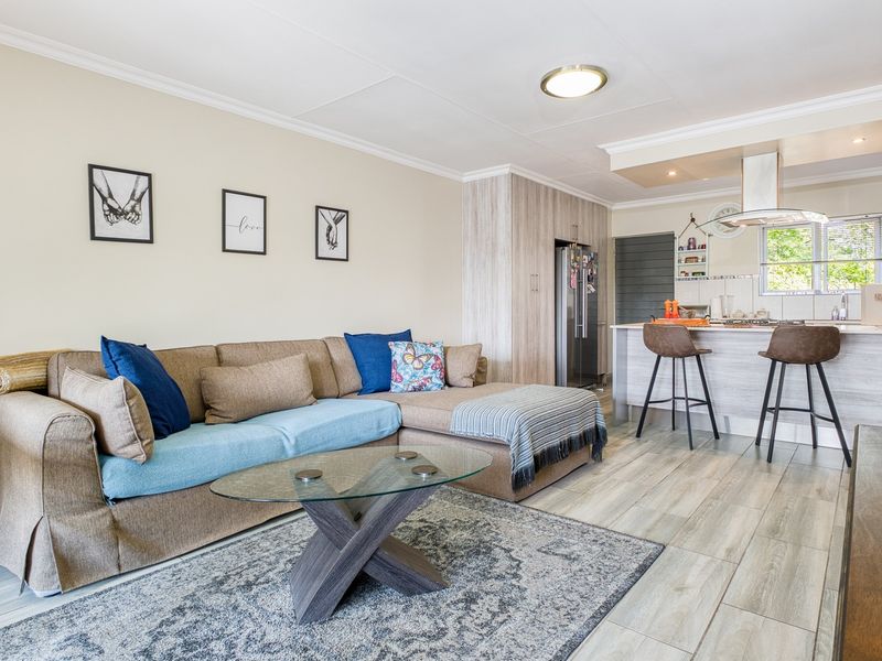 Open-plan living area featuring a modern kitchen with an island, breakfast bar, and light wood-look laminate flooring throughout.