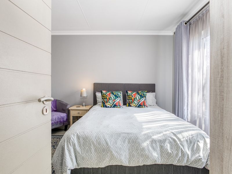 A well-maintained bedroom featuring neutral wall tones, coving, and natural light through a window with fitted curtain rods.