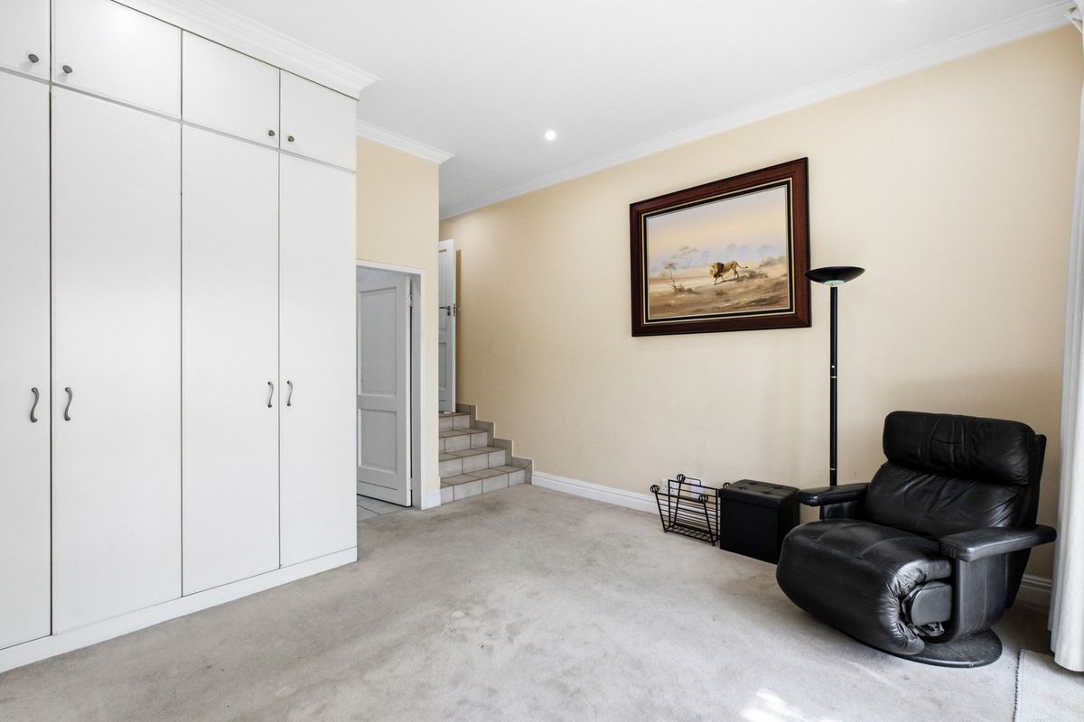 A bedroom featuring built-in cupboards, neutral wall finishes, and a tiled staircase leading to an adjacent area.
