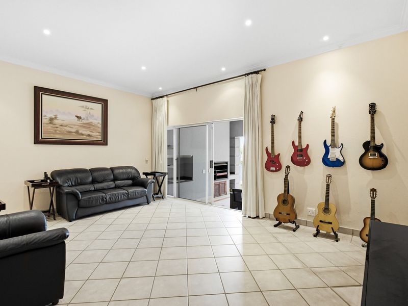 Spacious living room featuring neutral tiled flooring, recessed downlighting, and large sliding glass doors providing access to the outdoor patio area.