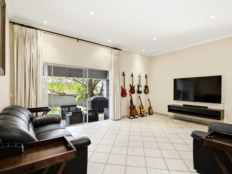 Spacious living room featuring tiled flooring, recessed lighting, and large sliding glass doors providing seamless access to the outdoor patio area.