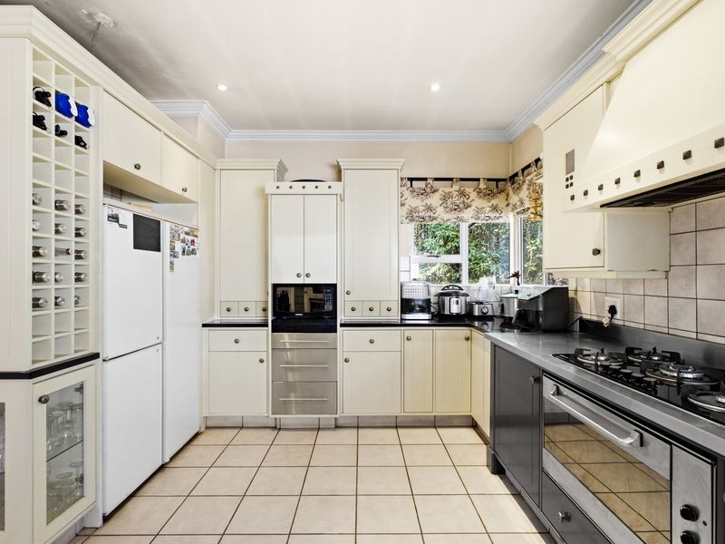 A functional kitchen featuring cream and dark grey cabinetry, stone countertops, a gas hob, built-in oven, and integrated wine storage.