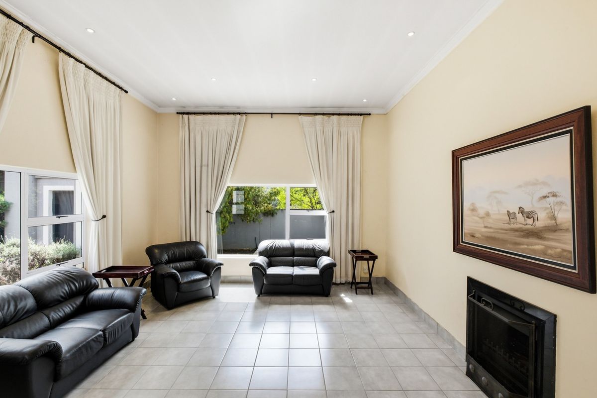 Spacious living room featuring tiled flooring, a built-in fireplace, and large windows with curtain tracks, offering a bright and functional living space.
