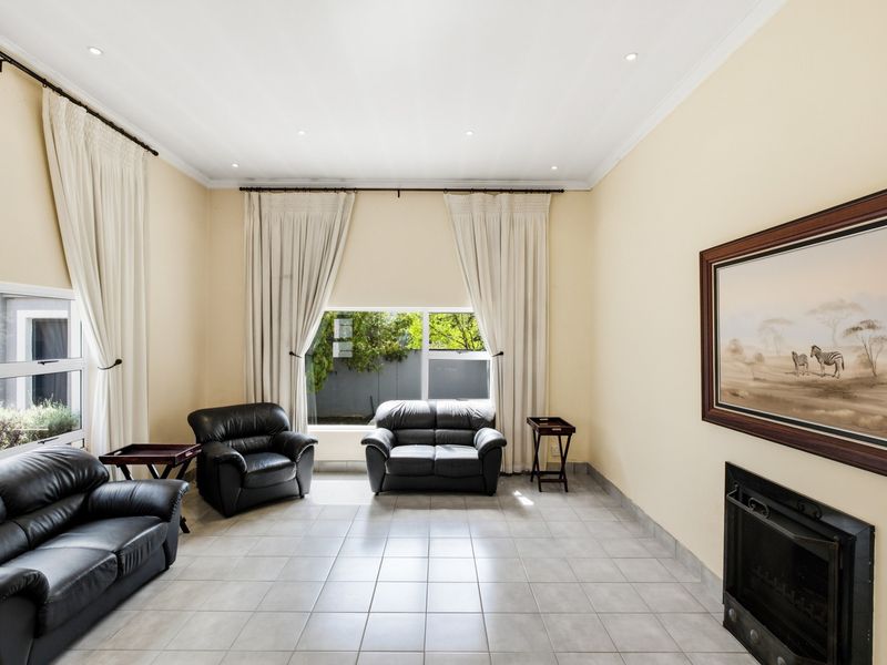 Spacious living room featuring tiled flooring, a built-in fireplace, and large windows with curtain tracks, offering a bright and functional living space.