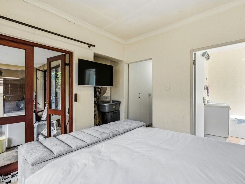 Bedroom featuring built-in cupboards, wooden door frames, and direct access to an en-suite bathroom.