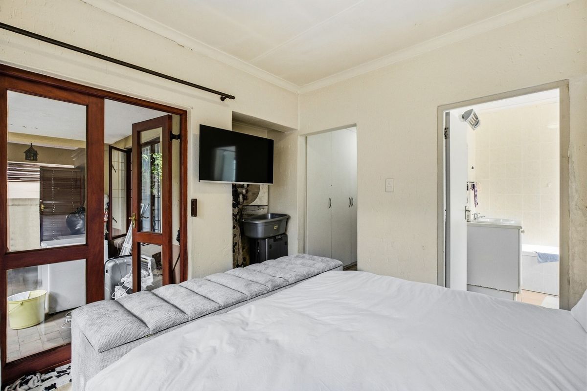 Bedroom featuring built-in cupboards, wooden door frames, and direct access to an en-suite bathroom.