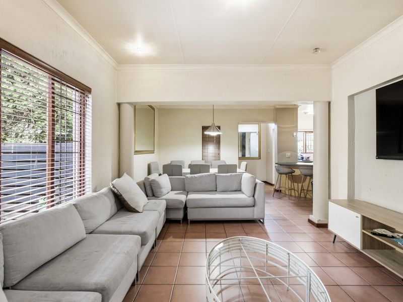 Spacious open-plan living and dining area featuring ceramic tile flooring, structural columns, and a breakfast bar connecting to the kitchen.