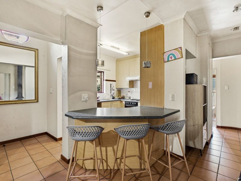 Open plan kitchen area featuring a breakfast bar, tiled flooring, and built-in cabinetry with integrated appliances.