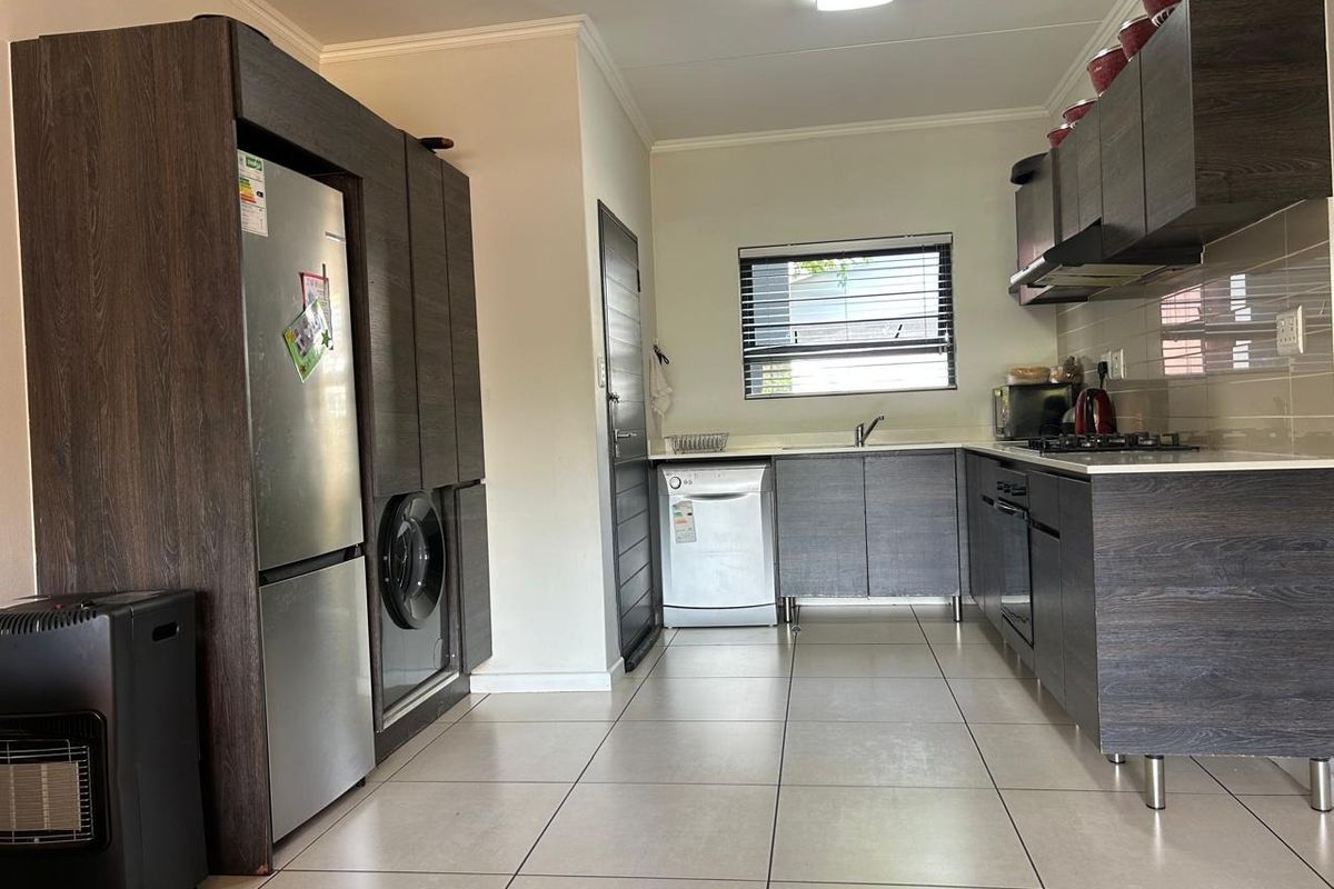 Modern kitchen featuring dark wood-grain cabinetry, built-in oven and hob, tiled flooring, and a functional layout with integrated appliance space.