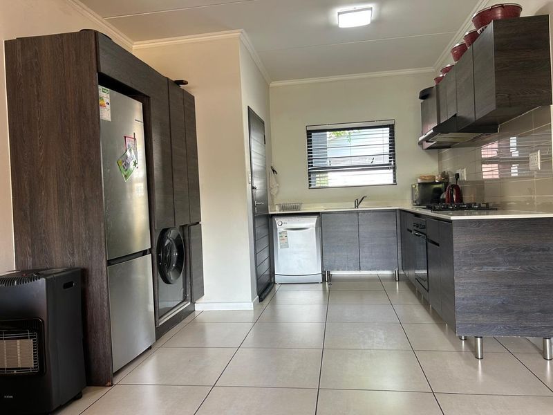 Modern kitchen featuring dark wood-grain cabinetry, built-in oven and hob, tiled flooring, and a functional layout with integrated appliance space.