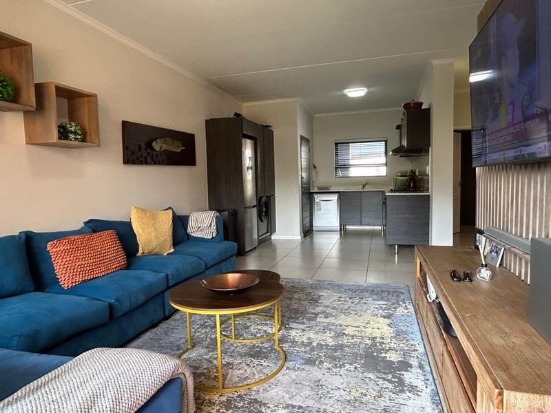 Open-plan living area featuring tiled flooring and a functional kitchen with built-in cabinetry and integrated appliances.