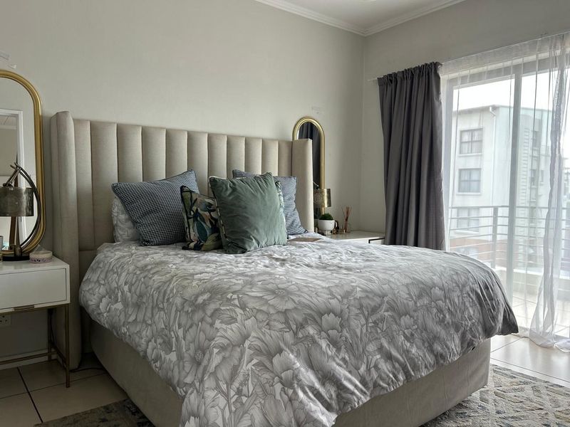 A well-maintained bedroom featuring tiled flooring and a sliding glass door providing access to a private balcony.