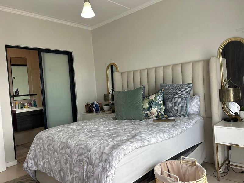 A well-maintained bedroom featuring neutral walls, tiled flooring, and an integrated en-suite bathroom with a sliding door entry.