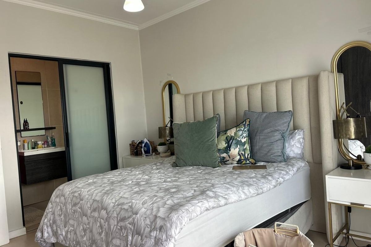 A well-maintained bedroom featuring neutral walls, tiled flooring, and an integrated en-suite bathroom with a sliding door entry.