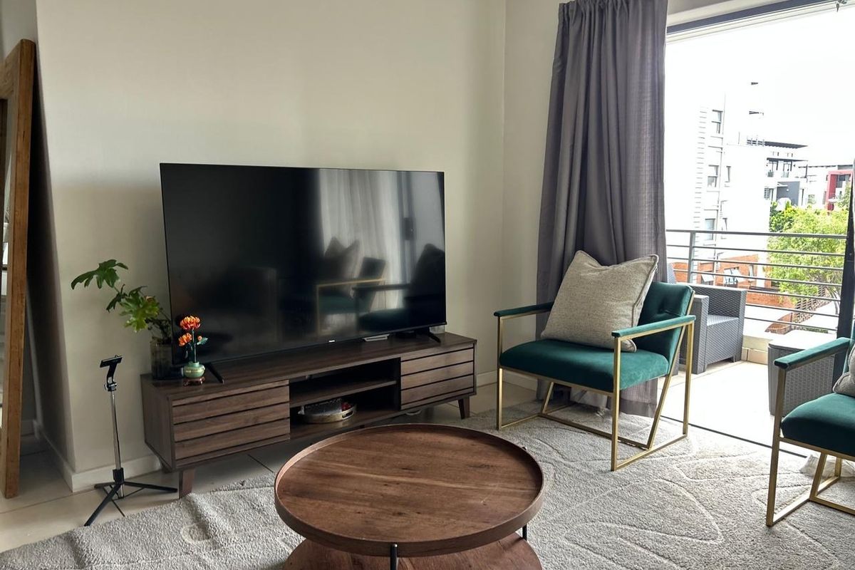 A bright living room featuring tiled flooring and a large sliding glass door providing direct access to an outdoor balcony.