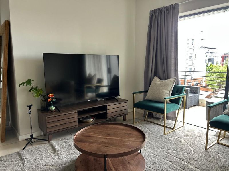 A bright living room featuring tiled flooring and a large sliding glass door providing direct access to an outdoor balcony.