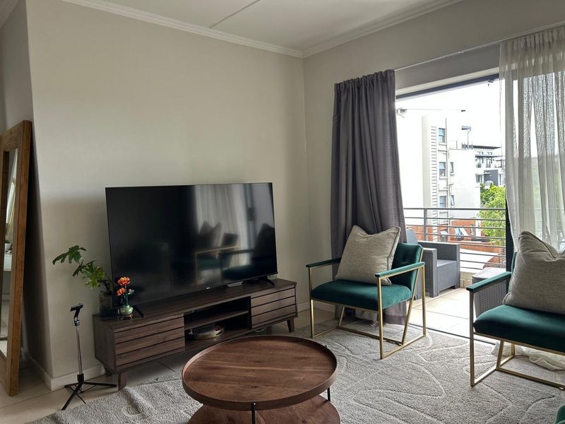 A bright living room featuring tiled floors and a large sliding glass door providing direct access to a private balcony.