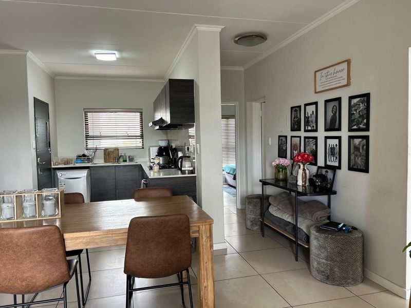 Open-plan living and dining area featuring a modern kitchen with dark cabinetry, tiled floors, and a functional layout connecting to the rest of the apartment.