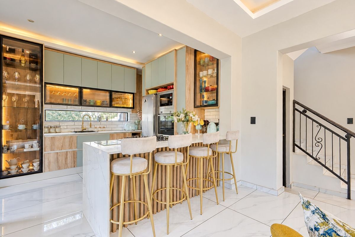 Modern kitchen featuring a marble-topped island, integrated cabinetry, built-in appliances, and elegant glass-front display units, seamlessly connected to the staircase area.