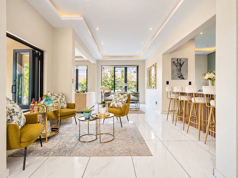 Spacious open-plan living area featuring high-gloss marble-look flooring, recessed ceiling lighting, and a modern built-in breakfast bar with timber detailing.