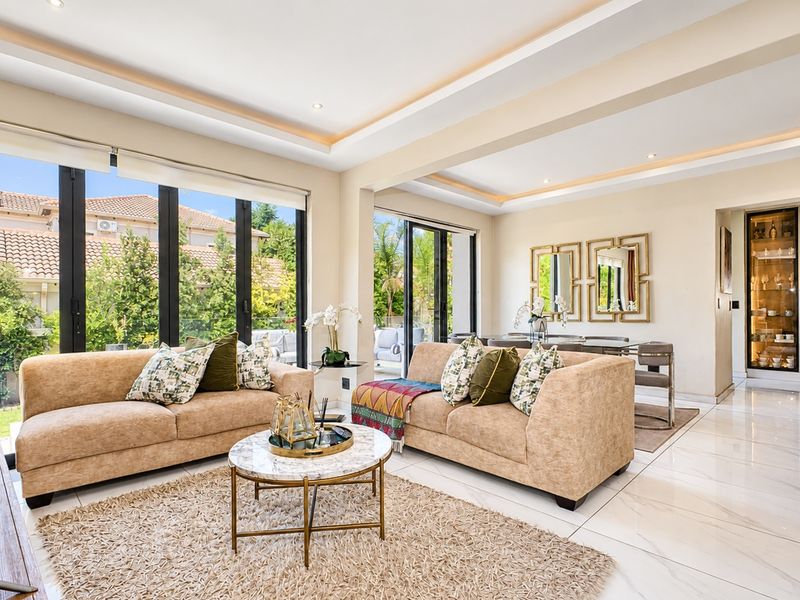 Spacious open-plan living and dining area featuring large format floor tiles, recessed ceiling lighting, and expansive sliding doors leading to the outdoor space.