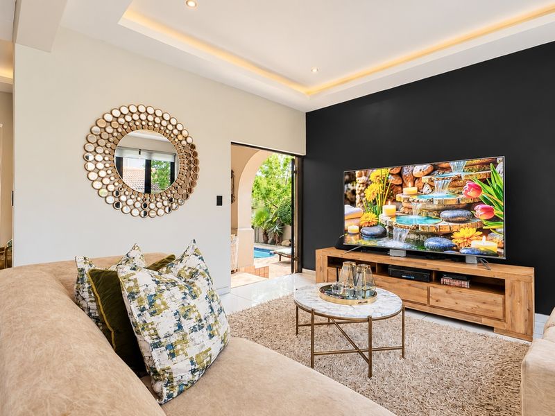 Modern living room featuring recessed cove lighting, sleek tiled floors, and direct access to an outdoor patio area.