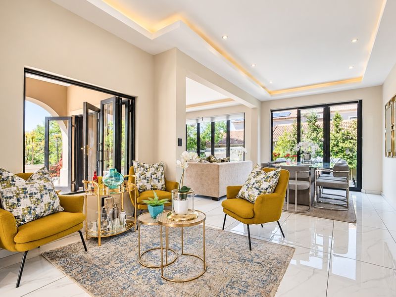 Spacious open-plan living and dining area featuring high-end porcelain tiling, modern recessed cove lighting, and large bi-fold doors providing seamless indoor-outdoor flow.