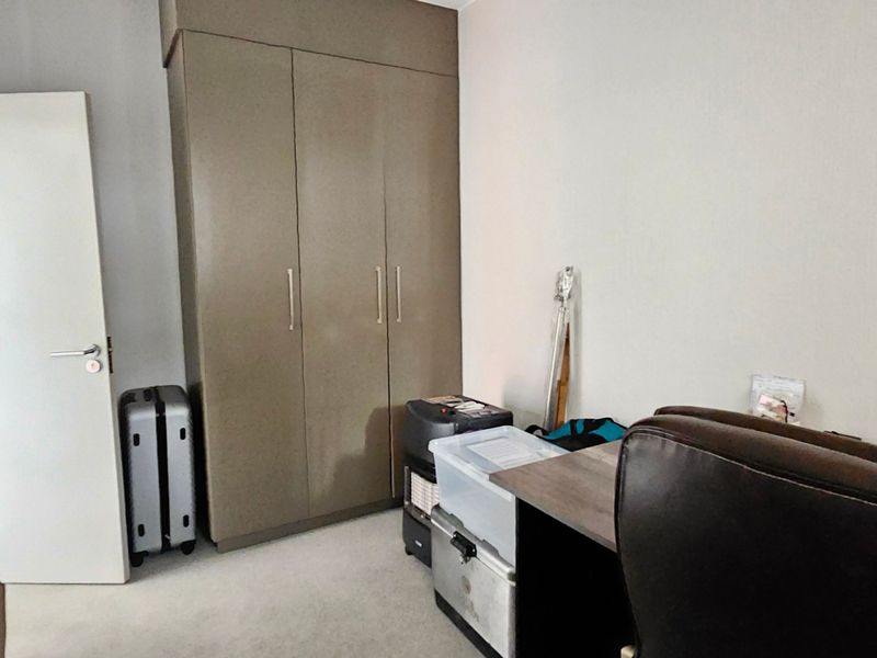 A bedroom featuring a neutral-toned built-in wardrobe and a standard internal door, providing functional storage space within the room.