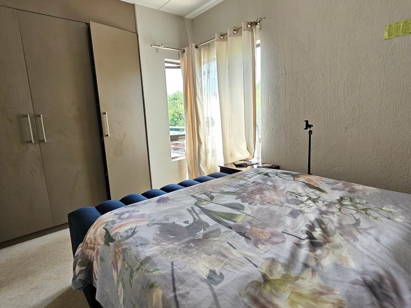 A bedroom featuring a built-in wardrobe and a window with curtain rod, providing natural light and storage space.