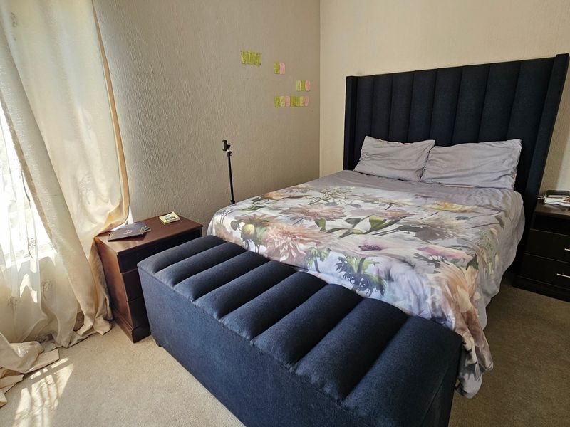 A standard bedroom featuring carpeted flooring and textured wall finishes, providing a functional space for rest.