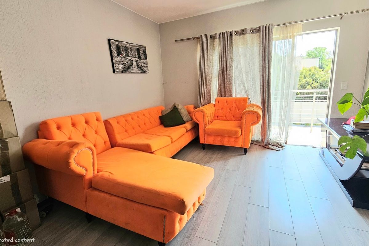 A living room featuring light-toned laminate flooring and a sliding glass door providing access to an outdoor balcony area.