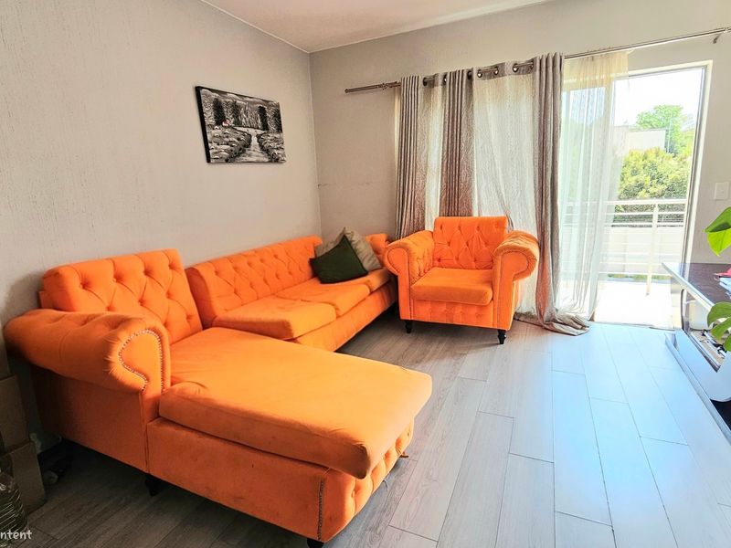 A living room featuring light-toned laminate flooring and a sliding glass door providing access to an outdoor balcony area.