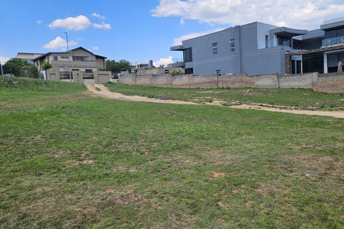 A vacant residential plot featuring a grass lawn and established boundary walls, situated in a developed neighborhood.