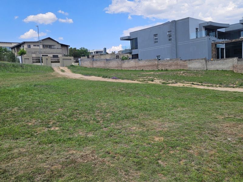 A vacant residential plot featuring a grass lawn and established boundary walls, situated in a developed neighborhood.