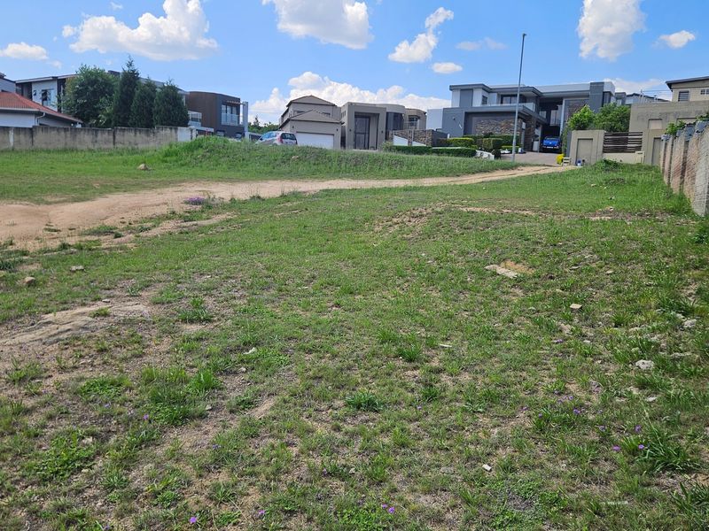 A vacant residential plot featuring a perimeter brick wall and grassed terrain, situated in a developed neighborhood.
