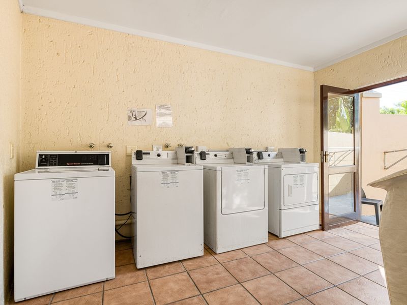 A functional laundry room featuring tiled flooring, textured walls, and direct access to an outdoor area.