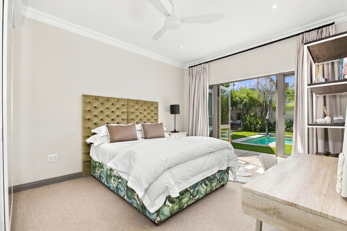 Spacious bedroom featuring neutral tones, crown molding, a ceiling fan, and direct access to a private patio and pool area through sliding glass doors.