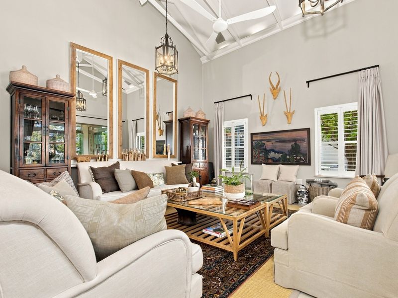 Spacious living room featuring a high vaulted ceiling with exposed rafters, ceiling fan, and plantation shutters, creating a bright and airy atmosphere.
