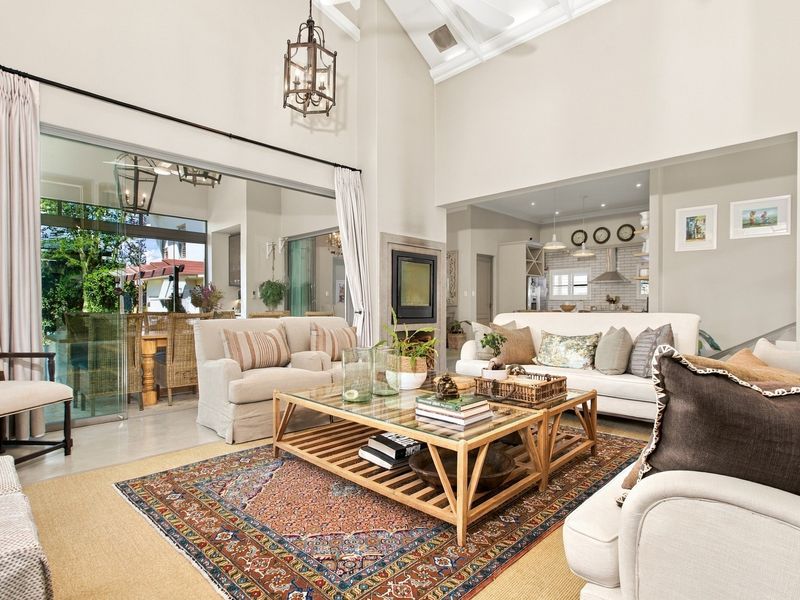 Spacious open-plan living area featuring vaulted ceilings with exposed rafters, a built-in fireplace, and large sliding glass doors leading to an outdoor patio.