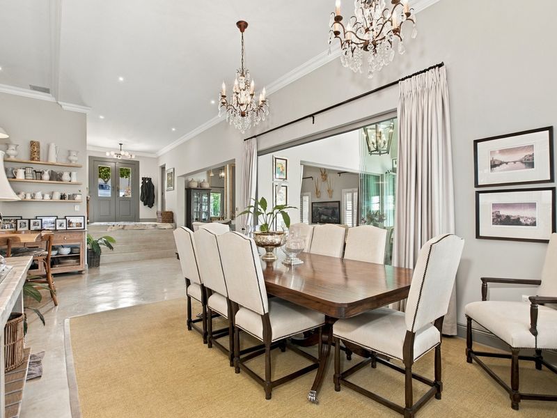 Elegant dining room featuring crystal chandeliers, crown molding, and a large wall mirror, creating a sophisticated space for formal entertaining.