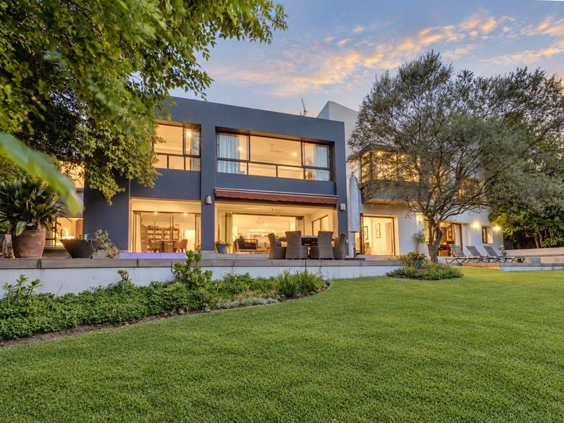 A beautifully presented rear elevation featuring a spacious lawn, raised patio area, and large sliding glass doors that seamlessly connect the indoor and outdoor living spaces.