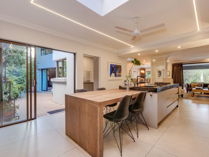 Modern open-plan kitchen and living area featuring a large island, skylight, and seamless flow to the outdoor patio through sliding glass doors.