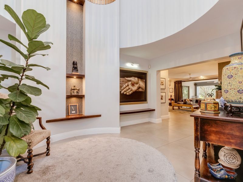 A spacious and elegant entrance hall featuring curved architectural walls, recessed display shelving with integrated lighting, and high-quality tiled flooring.