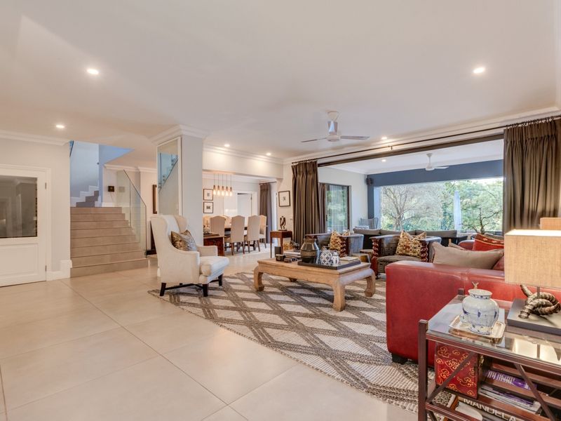 Spacious open-plan living and dining area featuring large sliding doors, modern tiled flooring, and a contemporary staircase with glass balustrades.
