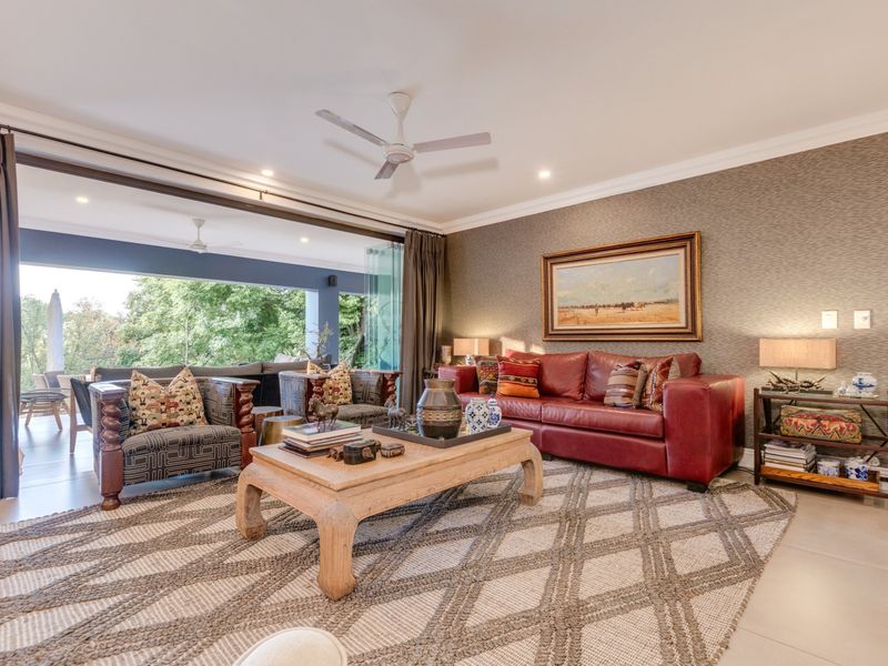 Spacious living room featuring elegant textured wallpaper, recessed lighting, a ceiling fan, and large stacking glass doors that open onto an outdoor patio area.