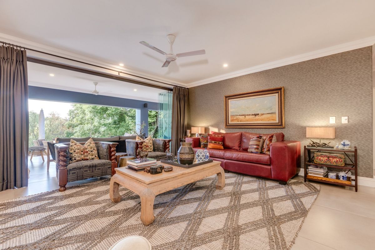Spacious living room featuring elegant textured wallpaper, recessed lighting, a ceiling fan, and large stacking glass doors that open onto an outdoor patio area.