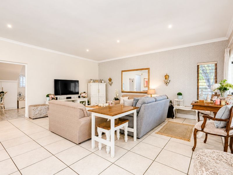 A well-maintained living room featuring neutral tiled flooring, recessed downlighting, and decorative textured wallpaper, offering a bright and comfortable living space.