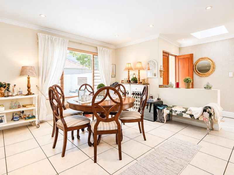A bright dining room featuring tiled flooring, recessed lighting, a skylight, and a built-in wine storage unit, creating a functional and inviting space.