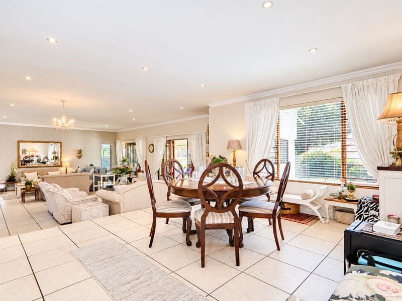Spacious open-plan living and dining area featuring tiled flooring, recessed lighting, and large windows that provide ample natural light and access to the patio.