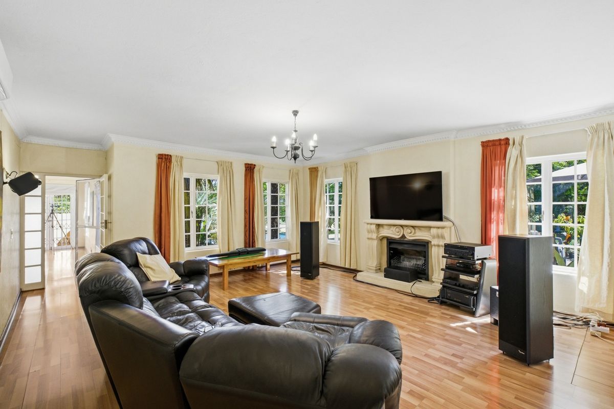 Spacious living room featuring laminate flooring, crown molding, and a decorative fireplace with a mantelpiece, complemented by natural light from multiple windows.